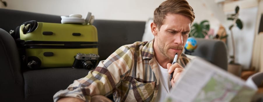 Man with serious face thinking, looking at travel map, planning vacation, going on holiday. Travelling concept