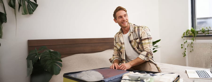 Happy husband, man going on holiday, tourist closing suitcase, preparing for vacation, unpacking luggage, smiling and looking enthusiastic. Tourism and travel concept