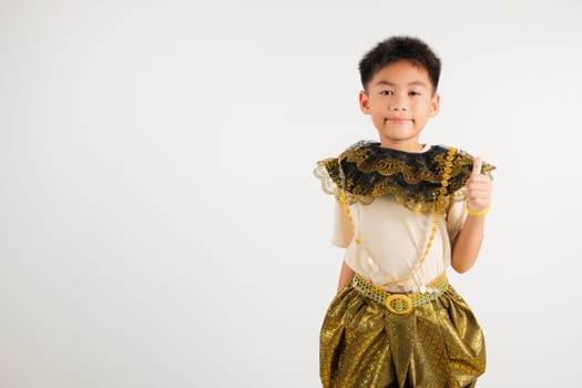 Portrait Thailand kid boy smiling traditional Thai dress costume makes thumbs up OK sign, symbolizing agreement, studio isolated white background, primary child radiates positivity and satisfaction