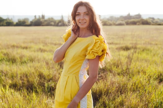 woman in yellow summer dress walking in wheat field at sunset