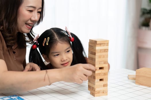 A joyful mother and daughter bonding while playing Jenga, fostering connection and creativity in a cozy home setting.