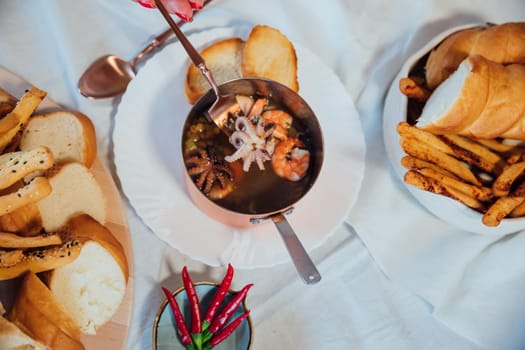 bonfire plate soup with sea products with bread as background