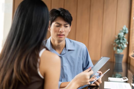 Two colleagues engaged in a serious conversation about financial strategies, reviewing data in a contemporary workspace.