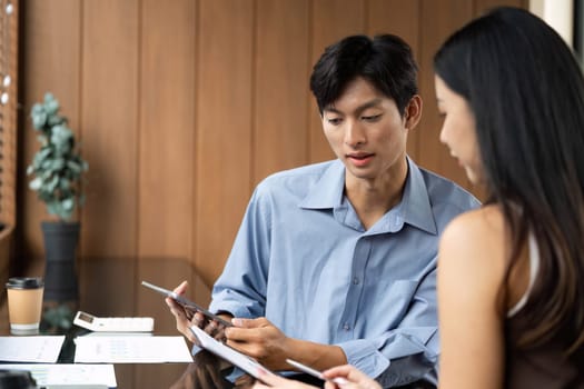 A business meeting between two colleagues focused on reviewing financial charts and strategies in a modern office setting.