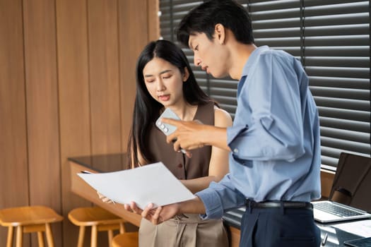 A businesswoman and businessman review project documents together, focusing on collaboration and strategy in a contemporary workspace.