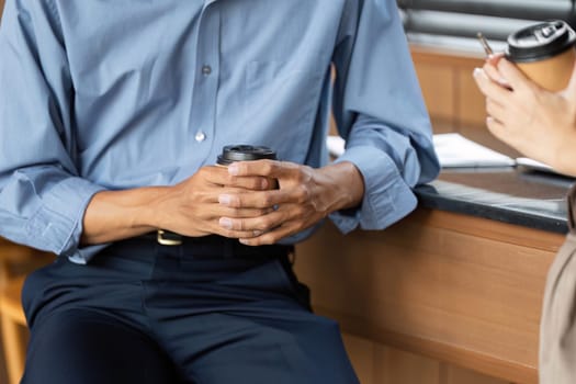 Hands of two professionals holding coffee cups while engaged in a meaningful conversation, emphasizing connection and collaboration.