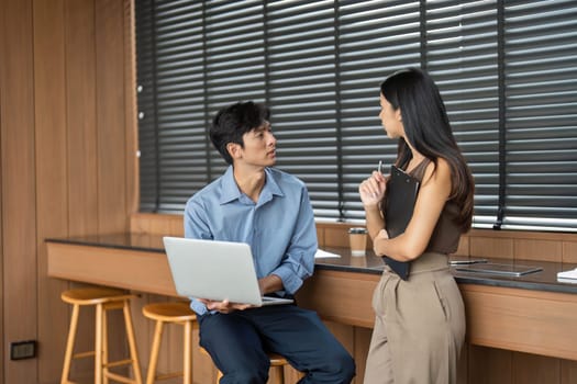 A young man and woman collaborate on a business project, sharing insights in a stylish office environment.