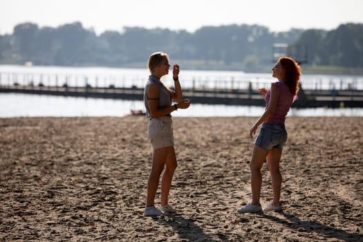 Two close friends share laughter and delight in ice cream on a beautiful, sunny beach, capturing joyful summer moments