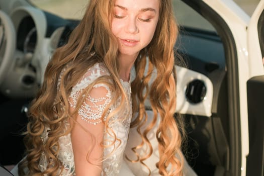 Young woman in white lace dress near car door. Wedding, elegance, femininity, movement, and soft natural beauty in everyday surroundings.