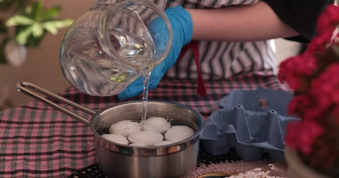 Water is being poured into a pot containing eggs, getting ready for boiling. This activity is part of the process of making colorful Easter eggs for decoration and celebration.