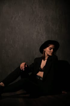 Beautiful woman in black jacket and hat on dark background