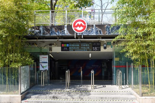 Shanghai, China - 1 April 2025: The entrance to People's Square Station (Exit 18) with bamboo groves in spring foliage. Sunny daylight highlights the contrast between urban infrastructure and natural elements.