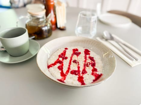 Healthy oatmeal with raspberry topping. Mindful eating and cozy cafe atmosphere.
