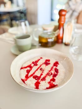 Healthy oatmeal with raspberry topping. Mindful eating and cozy cafe atmosphere.