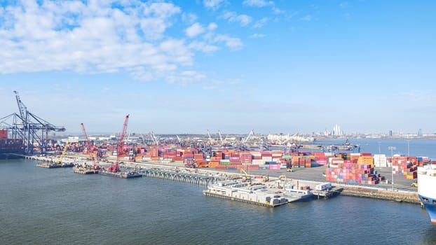 New York NY USA - 09.02.2024: Cargo containers stacked in a shipping yard near the sea with a city in the background.
