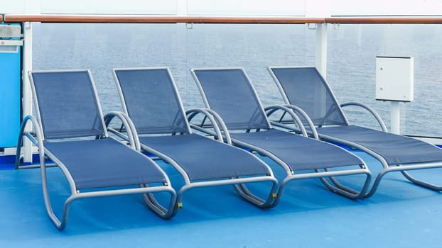 A serene view of blue deck chairs perfectly arranged in neat rows on a luxurious cruise ship deck