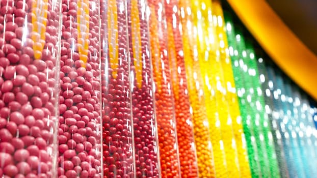 Colorful round candies displayed in clear plastic containers, arranged in a neat row. Perfect for backgrounds or illustrations related to the confectionery industry.