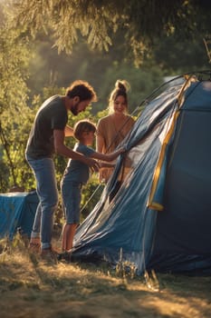 A happy family with their young son sets up a tent in the forest at golden hour. Great for portraying outdoor lifestyle, family bonding, parenting, and summer adventures in nature