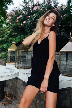 Beautiful woman in black summer dress posing and walking around town