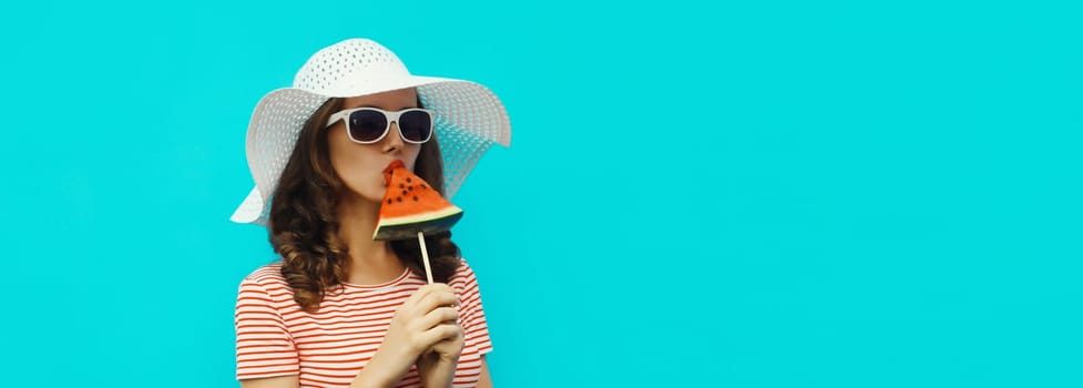 Summer portrait of stylish young woman with sweet juicy lollipop or ice cream shaped slice of watermelon fruit in white hat, glasses on blue background with copy space