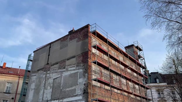 An incomplete building structure is currently showing exposed brick walls and construction scaffolding all around