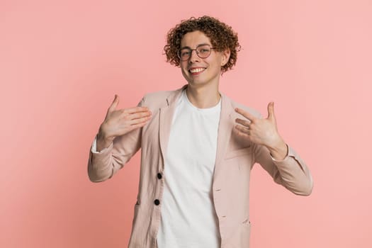 I am the best, choose me. Happy Caucasian man feeling very proud pointing himself, looking self-confident, overjoyed by success, making choice. Young guy isolated on studio pink background indoors