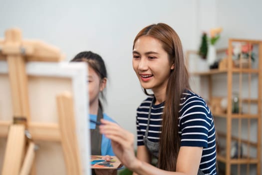 A mother teaches her child painting techniques during family time, sharing creativity and smiles in a cozy art space.