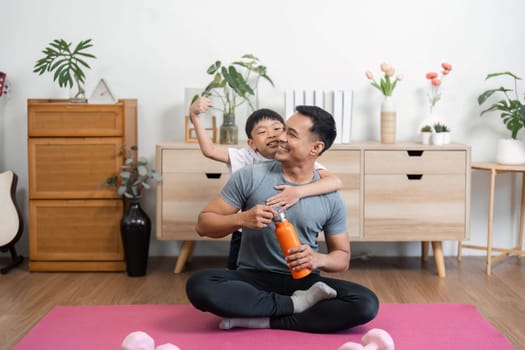 A father and son express joy after their workout, showcasing love and togetherness in a home gym while enjoying each other's company.