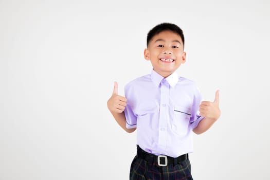 Portrait smile Asian little boy primary posing giving a thumbs up studio isolated white background, happy cute man kid wear school uniform plaid is expressing his approval, back to school concept