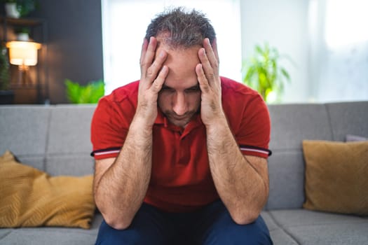 Man sitting alone at home looking sad and distraught.