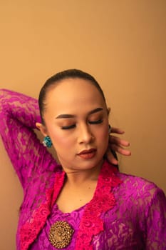 Asian woman touches her head while posing with makeup inside the studio