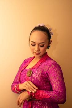 Balinese woman wearing a pink dress during the praying process in the temple at the Bali festival