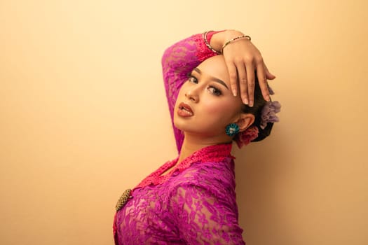 Balinese mother wearing a pink dress called kebaya and make-up before praying in the temple