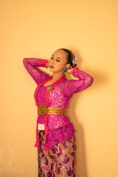 Balinese mother wearing a pink dress called kebaya and make-up before praying in the temple