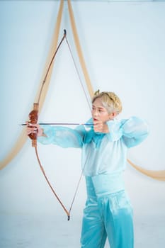 an Asian woman with blonde hair holding an arrow while wearing a blue dress in a white room