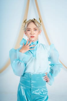 a princess with a blue dress and blonde hair posing very beautifully in front of a white background