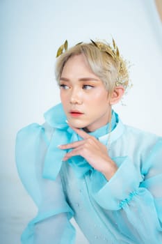 a royal princess posing with a golden crown and blonde hair very cutely in a white room