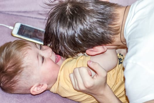 Teenage boy happily playing with his younger brother while looking after him. High quality photo