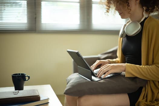 Close up of woman working from home on digital tablet with keyboard.