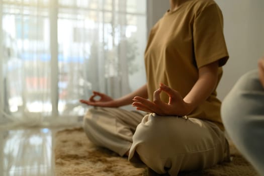 Peaceful young woman with curly hair practicing yoga at home.