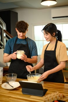 Young couple preparing pancake ingredients together in cozy kitchen.