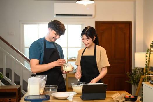 Young couple preparing pancake ingredients together in cozy kitchen.