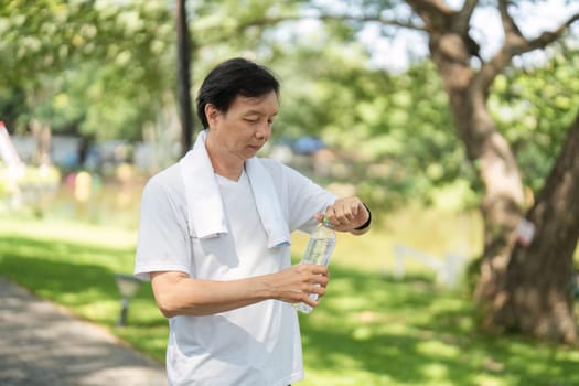 A man unscrews a water bottle cap after exercising in a park, emphasizing hydration and wellness.