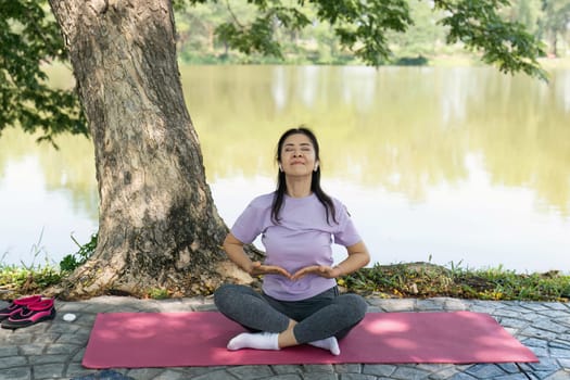 A woman practices yoga and meditation outdoors by a tranquil lake, promoting wellness and mindfulness in nature.