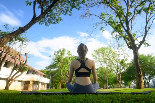 Rear view of a woman doing mindfulness meditation in a peaceful park.