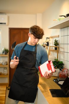 Caucasian man reading pancake mix instructions in kitchen, preparing to cook.