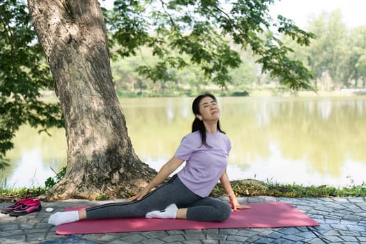 A woman enjoys yoga and stretching exercises near a calm lake, fostering wellness and relaxation in a natural environment.