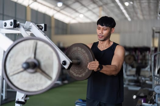A dedicated male athlete focuses on lifting weights in a modern gym, showcasing strength training and fitness commitment.
