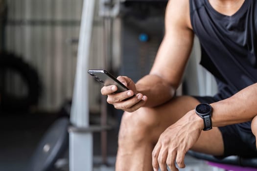 An athlete takes a moment to check his smartphone, integrating technology into his fitness routine for better results.