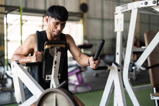 A focused male athlete engages in strength training using gym equipment, showcasing dedication to fitness.